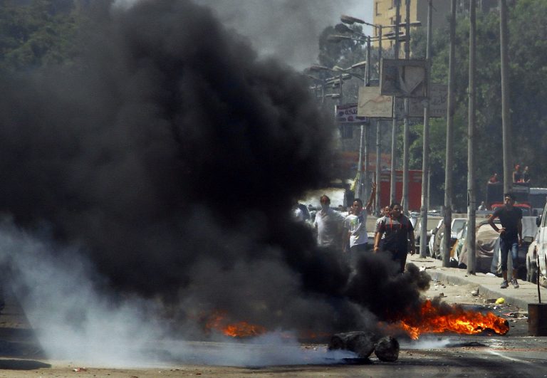 Supporters of Egypt's ousted President Mohammed Morsi stand behind smoke from burning debris set fire during clashes with security forces on a street in the Matariya neighborhood of Cairo, Egypt, Friday, Aug. 15, 2014. Islamist supporters held protests again a day after Thursday's anniversary of the dispersal of pro-Morsi sit-ins in which hundreds of demonstrators were killed. (AP Photo/Ahmed Abdel Fattah, El Shorouk Newspaper) EGYPT OUT