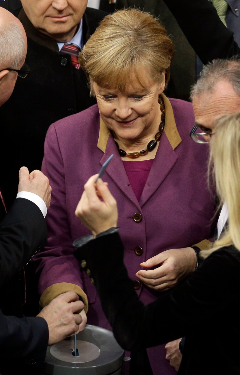   FILE - In this Nov. 30, 2012 file picture German Chancellor Angela Merkel casts her vote at the German federal parliament, Bundestag, in Berlin, Germany. The German Parliament has given its overwhelming backing to a deal aimed at trimming Greece's debt load and keeping the country financially afloat. Lawmakers voted 473-100 on Friday to back the complex deal reached by European finance ministers earlier this week. Germany's chancellor says in an interview published saturday Dec. 1, 2012 she understands the frustration felt by many Germans over the repeated bailout programs for Greece. But Angela Merkel also insists that helping debt-ridden Greece is in her country's self-interest because it helps stabilize the 17-nation eurozone on which Germany's prosperity depends. (AP Photo/Michael Sohn, File)  