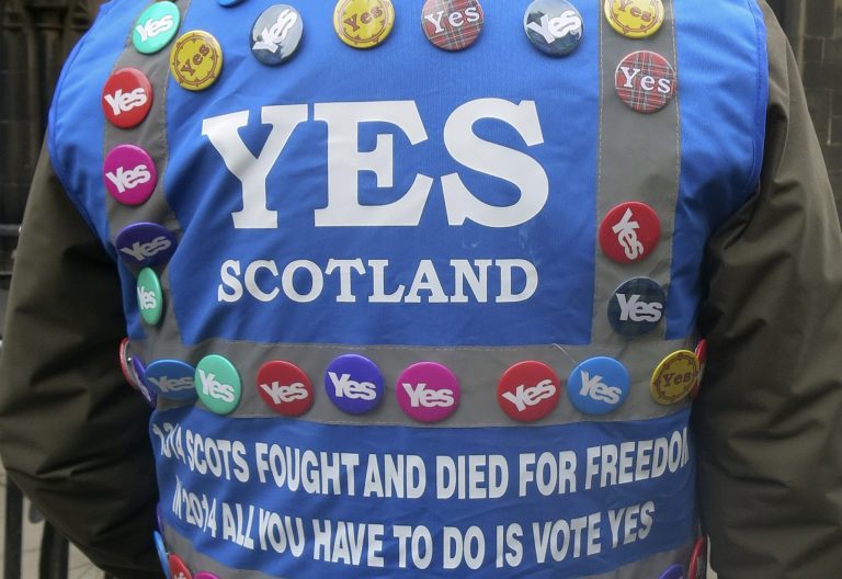 In this photo taken March 15, 2014 a man wears a multitude of 'yes' campaign badges during a pro-independence march in Edinburgh, Scotland for the upcoming vote on Scotland's independence from the United Kingdom. Scotland's swithering 