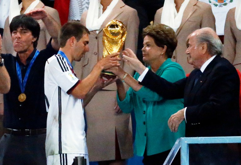 Germany's team captain Philipp Lahm, second left, receives the World Cup trophy by Brazil's President Dilma Rousseff and FIFA President Sepp Blatter, right, during the World Cup final soccer match between Germany and Argentina at the Maracana Stadium in Rio de Janeiro, Brazil, Sunday, July 13, 2014. (AP Photo/Frank Augstein)