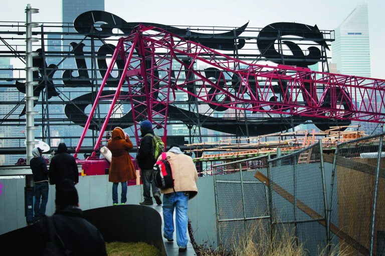 Onlookers observe a mangled crane at the construction site in the Queens borough of New York where it collapsed, Wednesday, Jan. 9, 2013 behind a big neon 