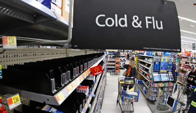 FILE - In this Friday, March 13, 2020, file photo, a woman looks at the few selections remaining in the cold and flu aisle of a Walmart near Warrendale, Pa. Walmart, the nationâs largest retailer and private employer, said late Saturday, March 14, 2020, it is limiting store hours to ensure they can keep sought-after items such as hand sanitizer in stock amid the coronavirus pandemic. 