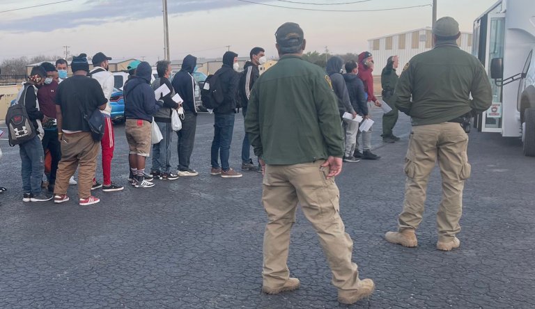 Migrants are released in Uvalde, Texas, as law enforcement officers stand nearby.