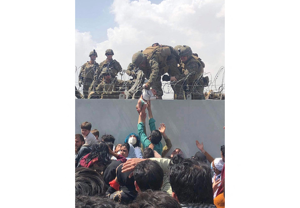 This image shows a U.S. Marine grabbing an infant over a fence of barbed wire during an evacuation at Hamid Karzai International Airport in Kabul on Aug. 19, 2021