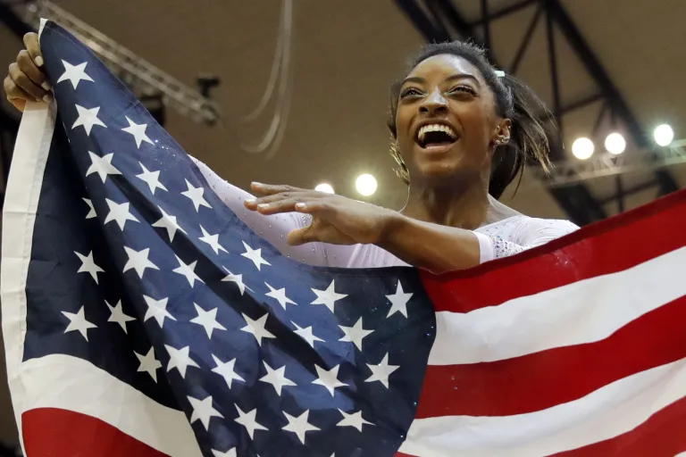 Gold medalist and four-times All-Around world champion Simone Biles celebrates with the national flag after the Women's All-Around Final of the Gymnastics World Chamionships at the Aspire Dome in Doha, Qatar, on Thursday.
