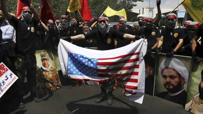 A demonstrator, covering his face in the style of Palestinian militants, holds a representation of the U.S. flag which is set on fire during the annual Quds, or Jerusalem Day rally in Tehran, Iran, Friday, May 31, 2019. Thousands of Iranians rallied Friday to mark Quds, or Jerusalem Day, which will see demonstrations across the Mideast as the Trump administration tries to offer an Israeli-Palestinian peace plan. 