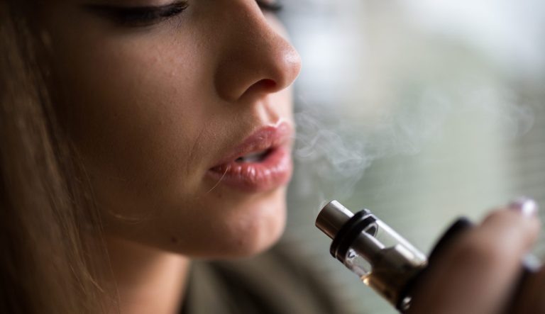 A teen smoking an e-cigarette.