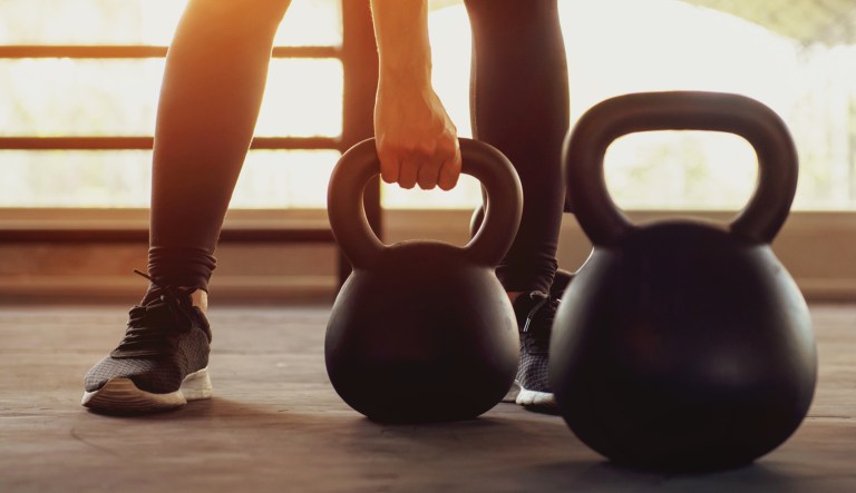 A person trains with a kettlebell in a gym.