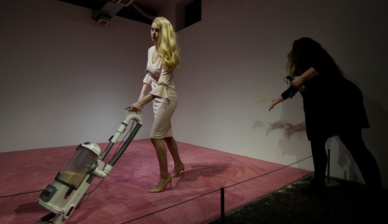 A spectator tosses crumbs for an Ivanka Trump lookalike to vacuum at Jennifer Rubell's art exhibit "Ivanka Vacuuming 2019" on Tuesday, Feb. 5, 2019, at Flashpoint Gallery in Washington. The art piece titled "Ivanka Vacuuming," runs through Feb. 17 at the Flashpoint Gallery.