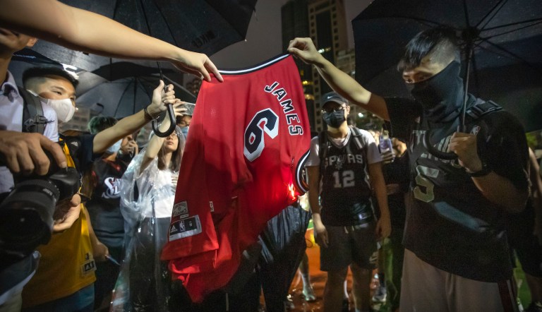 Demonstrators set a Lebron James jersey on fire during a rally at the Southorn Playground in Hong Kong, Tuesday, Oct. 15, 2019. Protesters in Hong Kong have thrown basketballs at a photo of LeBron James and chanted their anger about comments the Los Angeles Lakers star made about free speech.