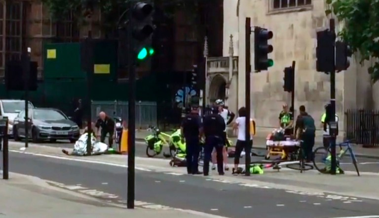 In this frame grab provided by UK Newsflare, emergency services attend the wounded after a car crashed into security barriers outside the Houses of Parliament in London, Tuesday, Aug. 14, 2018. A car plowed into pedestrians and cyclists near the Houses of Parliament in London during the morning rush hour Tuesday, injuring a number of people in what police suspect is the latest in a string of vehicle-based attacks in the British capital.