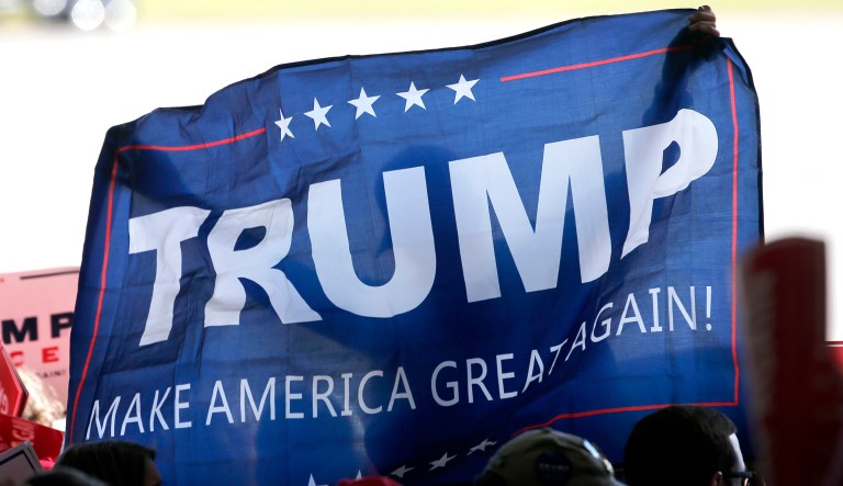 A supporter of Republican presidential candidate Donald Trump, holds up a campaign flag before Trump's arrival at a campaign stop at the Minneapolis International Airport Sunday, Nov. 6, 2016, in Minneapolis.