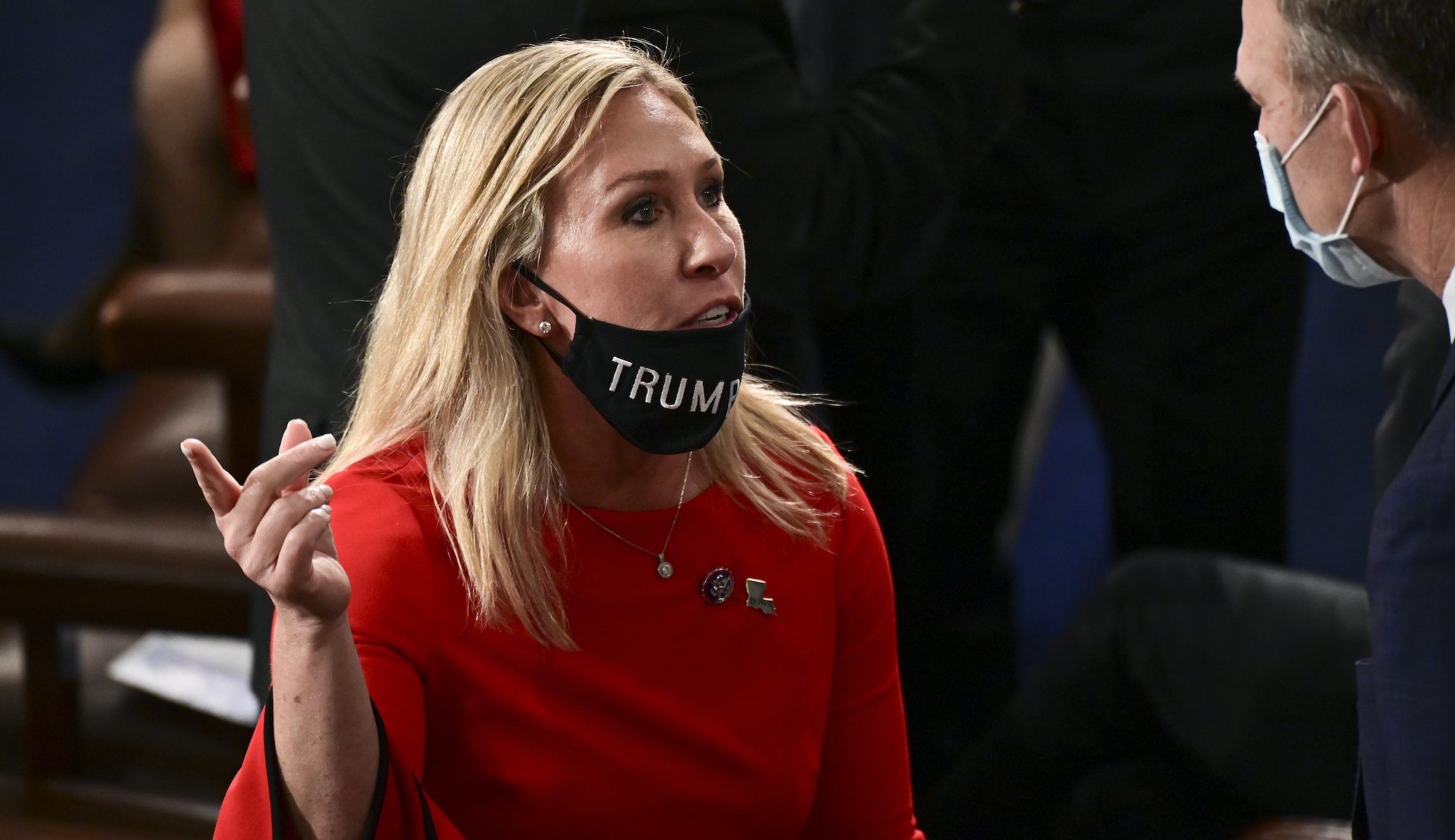 Rep. Marjorie Taylor Greene, R-Ga, speaks to a colleague with her "Trump Won" face mask pulled down below her mouth on the floor of the House before taking the oath of office on the opening day of the 117th Congress at the U.S. Capitol in Washington on Jan. 3, 2021.