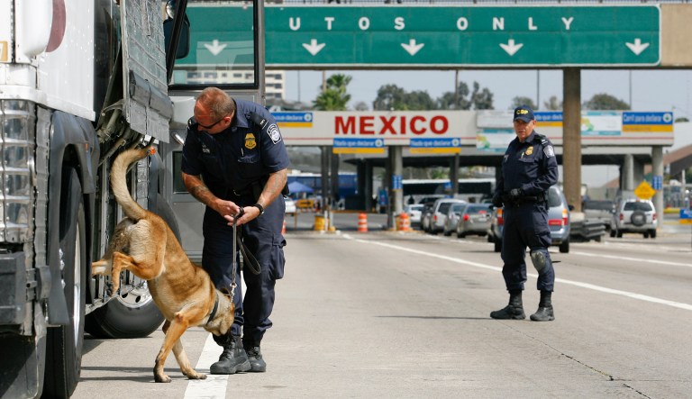 A U.S. Customs and Border Protection agent uses a dog to search a bus before it crosses the the border into Mexico.
