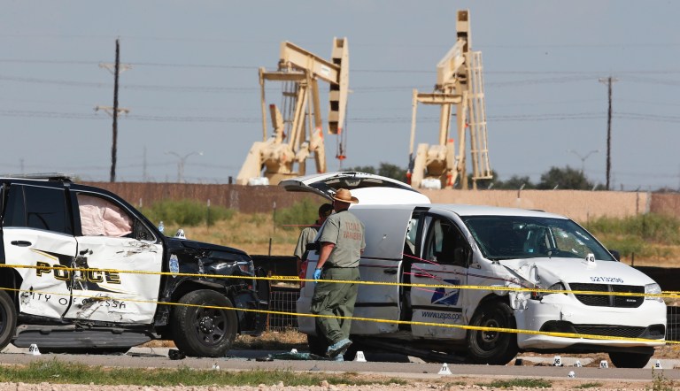 Law enforcement officials process the crime scene from Saturday's shooting which ended with the alleged shooter being shot dead by police in a stolen mail van, right, Sunday, Sept. 1, 2019, in Odessa, Texas. 