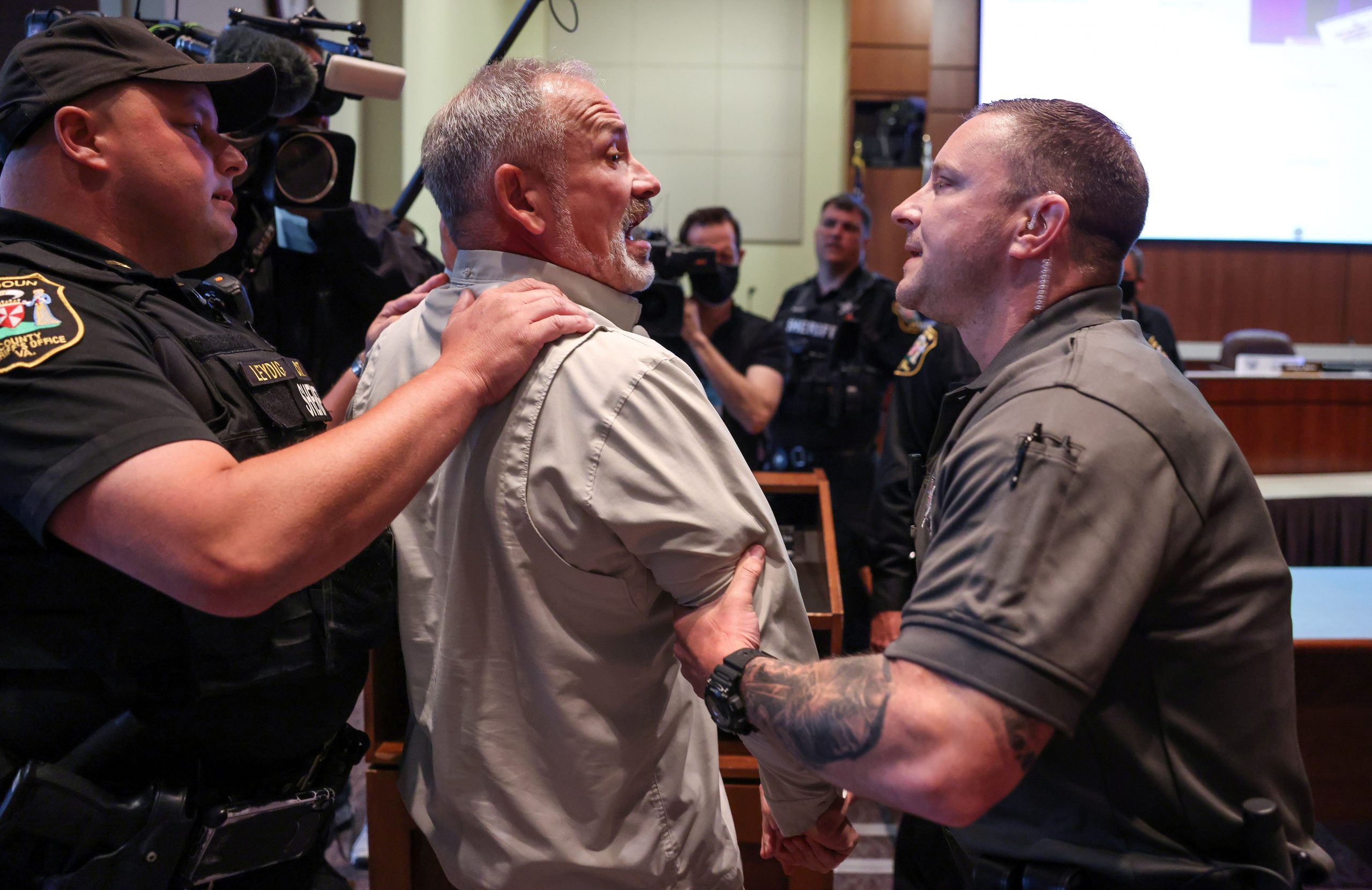A man is detained during a Loudoun County School Board meeting