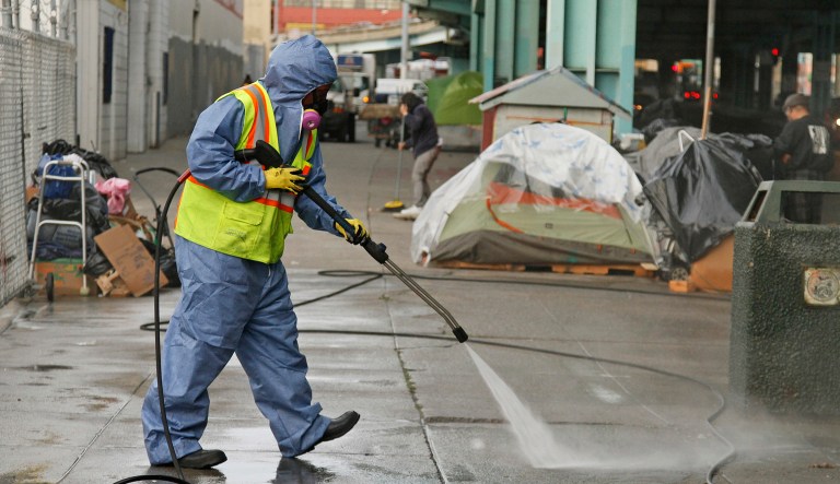 FILE - In this Feb. 26, 2016 file photo, a city worker uses a power washer to clean the sidewalk by a tent city along Division Street in San Francisco.