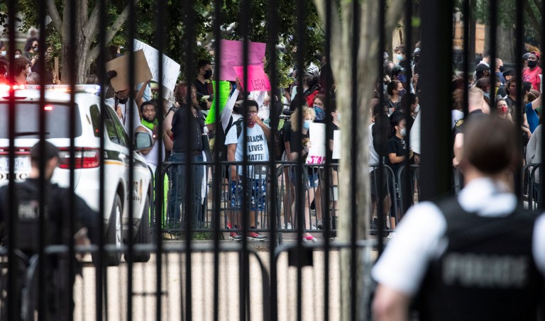 A U.S. Secret Service officer stands inside the fence at the White House as demonstrators protest the death of George Floyd, a black man who died in police custody in Minneapolis, Friday, May 29, 2020, in Washington.