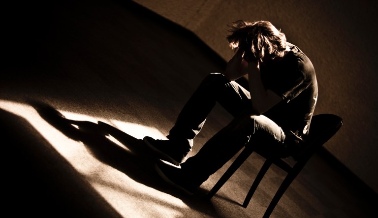 Depressed person slumps in chair.