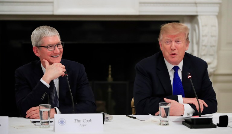 Apple Inc. CEO Tim Cook, left, reacts as President Donald Trump speaks during the American Workforce Policy Advisory Board's first meeting in the State Dining Room of the White House in Washington, Wednesday, March 6, 2019.