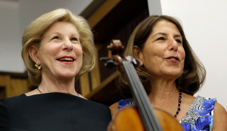 Sisters Jill Totenberg, left, Nina Totenberg, center, and Amy Totenberg pose for pictures with the Ames Stradivarius violin during a news conference in New York, Thursday, Aug. 6, 2015.  The instrument was stolen from their father, renowned violinist Roman Totenberg, 35 years ago when he left his beloved Stradivarius in his 