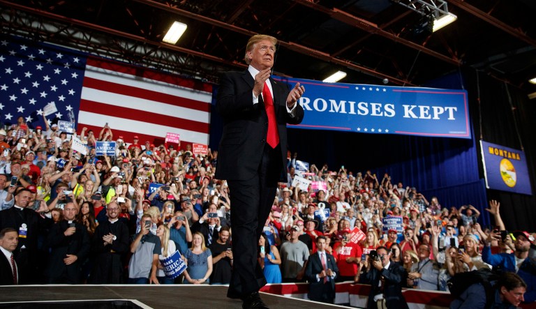 FILE - In this July 5, 2018, file photo, three of the four Roman Catholic priests are visible in the front row at lower left as President Donald Trump arrives to speak during a rally at the Four Seasons Arena at Montana ExpoPark in Great Falls, Mont. A Roman Catholic bishop in Montana criticized four priests who attended Trump's rally in Great Falls last week for wearing their black clerical garb while prominently seated in the front row directly behind the president.