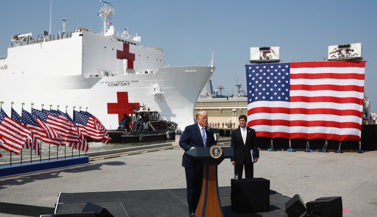 President Donald Trump speaks in front of the U.S. Navy hospital ship USNS Comfort at Naval Station Norfolk in Norfolk, Va., Saturday, March 28, 2020. The ship is departing for New York to assist hospitals responding to the coronavirus outbreak. Defense Secretary Mark Esper is at right.