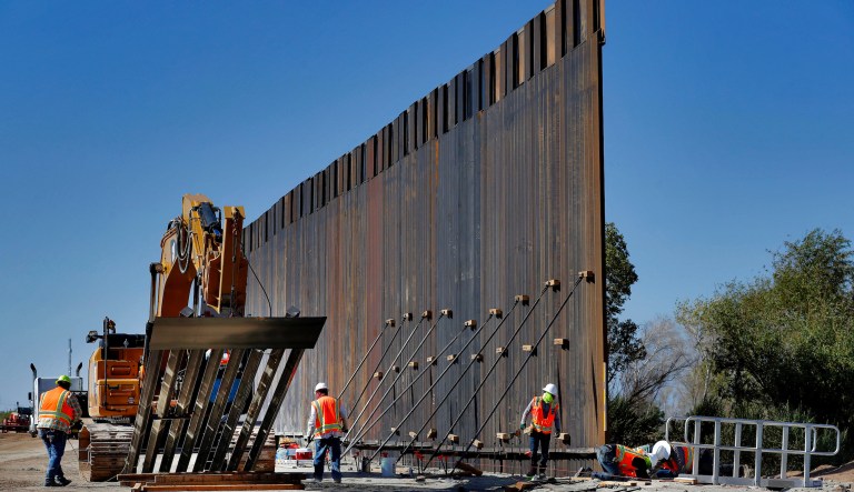Government contractors erect a section of Pentagon-funded border wall along the Colorado River, Tuesday, Sept. 10, 2019 in Yuma, Ariz. The 30-foot high wall replaces a five-mile section of Normandy barrier and post-n-beam fencing along the the International border that separates Mexico and the United States. Construction began as federal officials revealed a list of Defense Department projects to be cut to pay for President Donald Trump's wall.