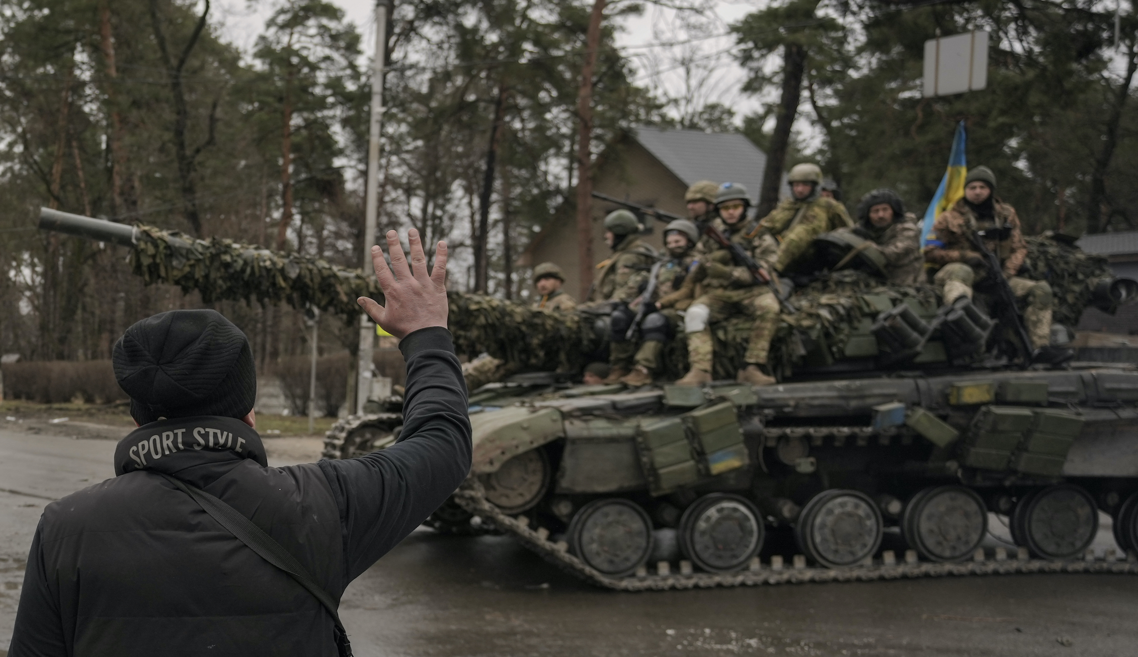 A man waves to Ukrainian servicemen riding on a tank outside Kyiv, Ukraine, on Saturday.