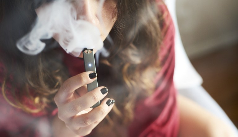 A person smokes a Juul Labs Inc. e-cigarette in this arranged photograph taken in the Brooklyn Borough of New York, U.S., on Sunday July 8, 2018.