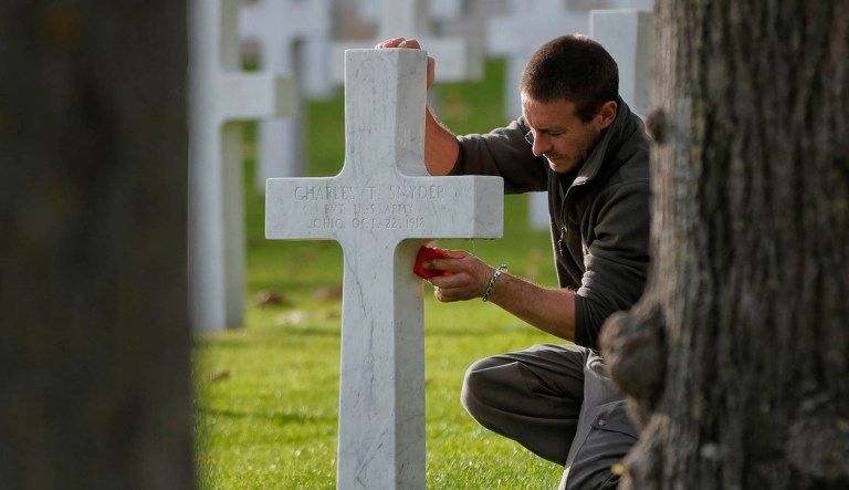 A cemetery employee cleans the cross of an American serviceman killed during WWI ahead of celebrations of the WWI centenary at the American Cemetery in Suresnes, on the outskirts of Paris, France, Friday, Nov. 9, 2018.