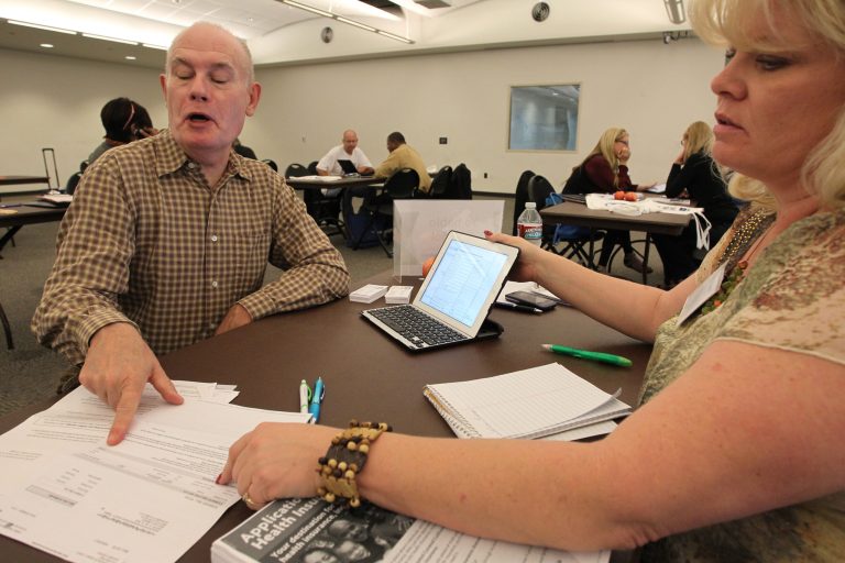 A healthcare reform specialist helps an individual compare health insurance plans. (Photo by David McNew/Getty Images)