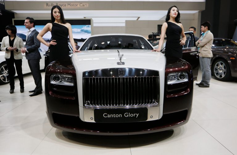 FILE - In this Nov. 21, 2013 file photo, models pose beside the Rolls-Royce Canton Glory at the company's booth during Guangzhou 2013 Auto Show in China's southern city of Guangzhou. Britain-based Rolls-Royce on Tuesday, July 8, 2014 said that global sales in the first half of the year were up 33 percent compared with the same period in 2013.  (AP Photo/Kin Cheung, File)