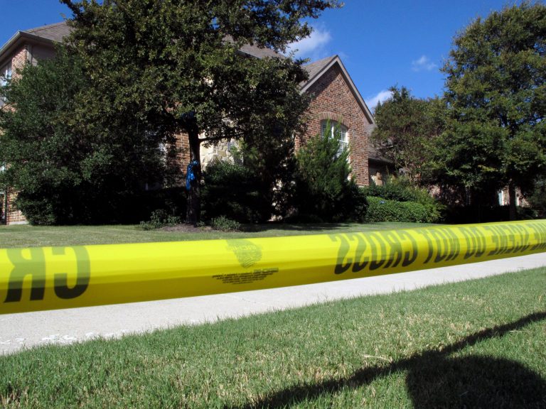 In this Thursday, Sept. 4, 2014 photo, police tape marks off the exterior of a Frisco, Texas, home were two bodies found Wednesday. The bodies of a man and a woman were found at the suburban Dallas home where a 10-year-old boy was found dead in January, whose mother,  Pallavi Dhawan was accused of killing him, police said. A medical examiner's report later said a natural cause was the most likely cause of the Jan. 29 death of the boy, Arnav Dhawan. (AP Photo/Nomaan Merchant)