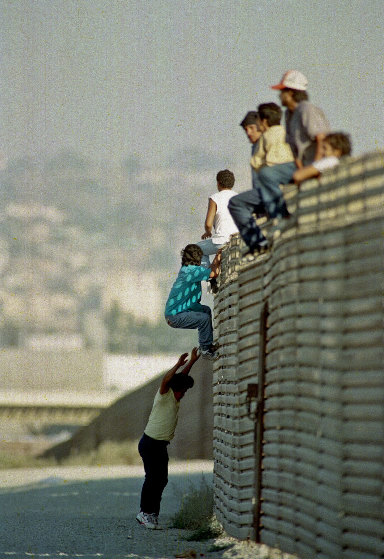 ADVANCE FOR USE MONDAY, FEB. 25, 2013 AND THEREAFTER - FILE - In this Oct. 14 1991 file photo, a group of illegal Mexican immigrants jump from a border fence to enter the United States, near Tijuana, Mexico. With new fencing and tougher enforcement the 1,954-mile border with Mexico is more difficult to breach than ever. (AP Photo/Lenny Ignelzi)