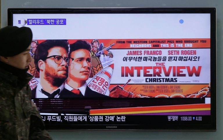 A South Korean army soldier walks near a TV screen showing an advertisement of Sony Picture's 