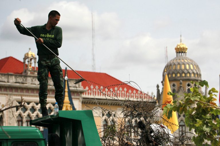 A Thai soldier places barbed wire on the ground after pulling it out from a canal near the Government House during a cleanup operation Friday, June 6, 2014 in Bangkok. Thailand's new military government moved against two of its top targets on Thursday, capturing a top organizer of protests against its recent takeover and launching a probe into the finances of the former elected prime minister. (AP Photo/Wason Wanichakorn)
