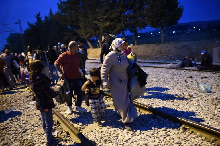 Refugees and migrants walk on the railway tracks as they wait to pass from the northern Greek village of Idomeni to southern Macedonia, Sunday, Sept. 20, 2015. (AP Photo/Giannis Papanikos)