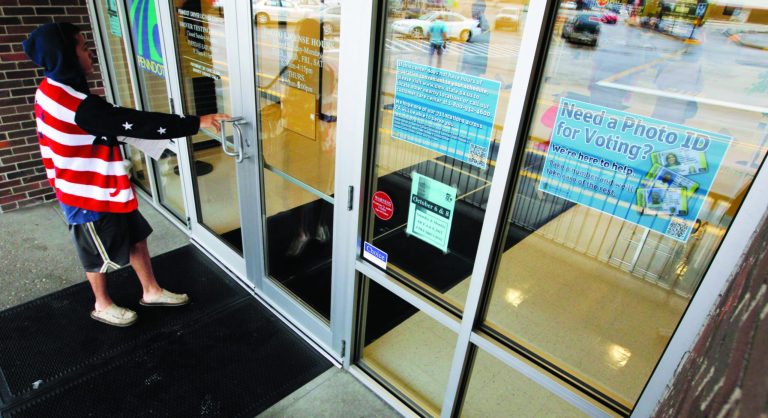 FILE - In this Sept. 26, 2012 file photo, A man heads into the the Penndot Drivers License Center in Butler, Pa., near a sign telling of the requirement for voters to show an acceptable photo ID to vote. Some political momentum could be on the line in a judge's forthcoming ruling on Pennsylvania's tough new voter identification law. Commonwealth Court Judge Robert Simpson is expected to rule Tuesday. That's just five weeks before voters decide whether to re-elect President Barack Obama, a Democrat, or replace him with Mitt Romney, a Republican. (AP Photo/Keith Srakocic, File)