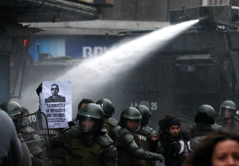   Riot police uses a water cannon to disperse a demonstration against the late Gen. Augusto Pinochet in Santiago, Chile, Sunday June 10, 2012. Police used tear gas and water cannons to try to disperse hundreds of anti-Pinochet demonstrators protesting the premiere of a documentary, casting him as a national hero who saved Chile from communism, about the run-up to his dictatorship years.(AP Photo/Luis Hidalgo)  