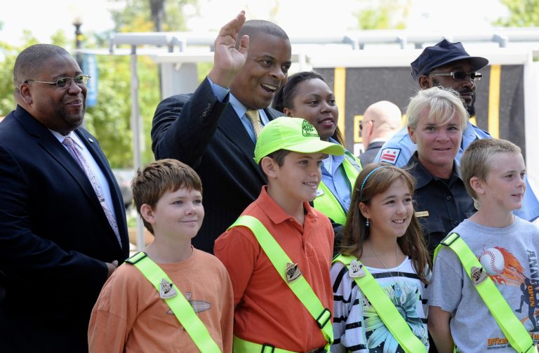   Transportation Secretary Anthony Foxx, center, and National Highway Traffic Safety Administration Administrator (NHTSA) David Strickland, left. stand with students wearing crossing guard belts during a news conference outside the Transportation Department in Washington, Monday, Aug. 5, 2013. Secretary Foxx announced a new set of tools to help communities combat the rising number of pedestrian deaths that have occurred over the last two years. (AP Photo/Susan Walsh)  