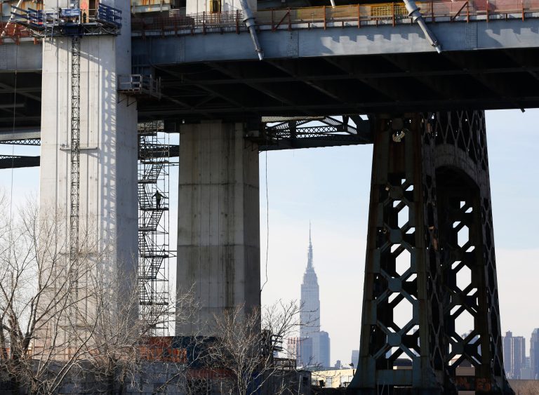 A worker climbs a staircase, left, as construction continues above him on the eastbound Kosciuszko Bridge carrying traffic on the Brooklyn-Queens Expressway (Interstate 278) over Newtown Creek between Brooklyn and Queens, Sunday, Jan. 15, 2017, in New York. The first of two, side-by-side, cable-stayed bridges will open in the spring of 2017, just three years after state transportation officials awarded $555 million to a project team to construct it. The new spans replace the original Kosciuszko Bridge, built in 1939. The Empire State Building is seen in the background. (AP Photo/Kathy Willens)