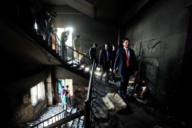   FILE - In this Monday, Nov. 26, 2012 file photo, Bangladeshi officials inspect the burned out garment factory on the outskirts of Dhaka, Bangladesh. A week after a blaze at the factory killed 112 workers, a glaring question remains unanswered: How, exactly, did brands worth fortunes end up in such a place? Retailers like Wal-Mart and Sears, whose merchandise was found in the embers, are loathe to explain. But piecing together their limited answers with records and the insight of industry experts reveals a complex and ever-morphing supply chain, in which Tazreen Fashions Ltd. was but a single, completely interchangeable link. (AP Photo)  