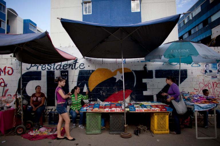  Street vendors work in front of a mural that reads 