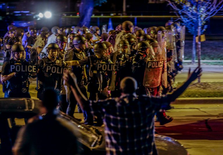 Police move in on a group of protesters throwing rocks at them in Milwaukee, Sunday, Aug. 14, 2016. (AP Photo/Jeffrey Phelps)