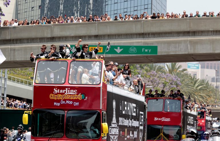   Hockey fans watch from a bridge as the Los Angeles Kings ride atop buses during a parade celebrating the team's NHL hockey Stanley Cup championship in Los Angeles, Thursday, June 14, 2012. (AP Photo/Richard Vogel)  