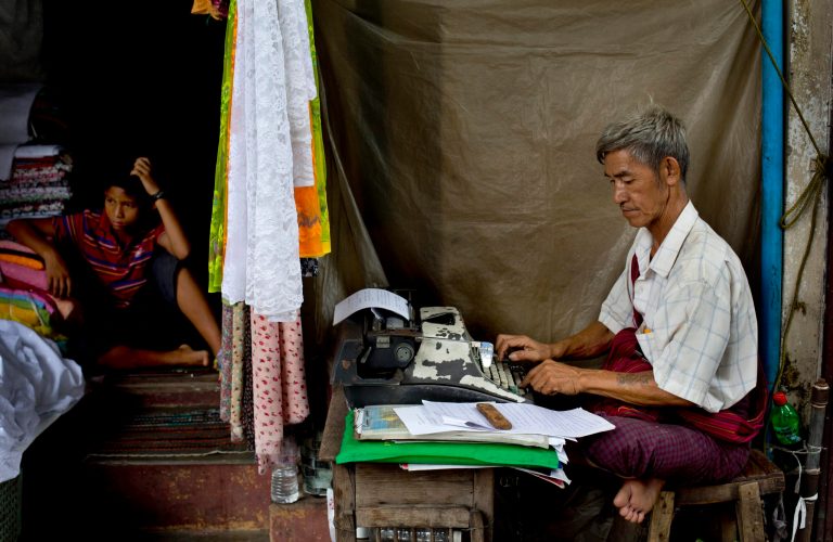 In this May 22, 2014 photo, Aung Myint types a document from his sidewalk stand in Yangon, Myanmar. The 67-year-old insists typewriters still have some advantages over computers. 