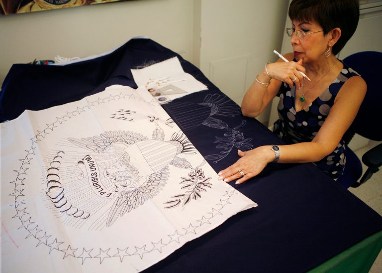   In this Tuesday, June 12, 2012 photo, Hue Nguyen, 59, of Philadelphia, draws the presidential flag pattern for the fabric workers at the Defense Logistics Agency in Philadelphia. About 10 miles from the house where Betsy Ross is believed to have sewn the first U.S. flag, Nguyen is one of about a dozen seamstresses at a military supply operation who are the sole producers of the hand-stitched presidential banners. (AP Photo/Brynn Anderson)  