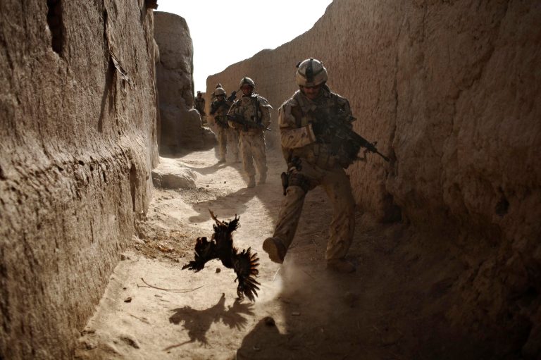FILE - In this Saturday, Sept. 11, 2010 file photo, a Canadian soldier with the 1st RCR Battle Group, The Royal Canadian Regiment, chases a chicken seconds before he and his unit were attacked by grenades shot over the wall during a patrol in Salavat, southwest of Kandahar, Afghanistan. Anja Niedringhaus, a courageous and immensely talented Associated Press photographer who has covered everything from sports to war, was killed while covering elections in Afghanistan on Friday April 4, 2014. Niedringhaus was in a car in eastern Afghanistan with AP reporter Kathy Gannon when, according to a freelancer who was with them, an Afghan policeman approached them, yelled 
