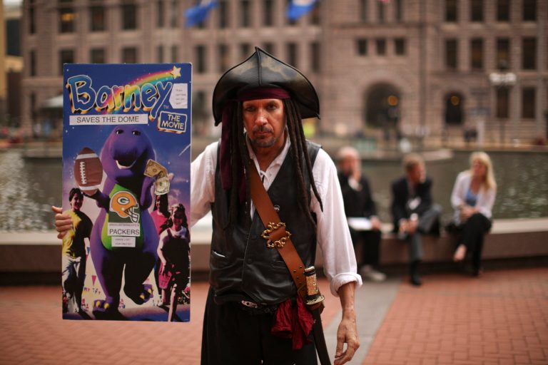 In this Sept. 18, 2013 photo, Minneapolis mayoral candidate, Captain Jack Sparrow holds up a poster for a proposal he has put forward for community ownership of an NFL football team. Sparrow, who initially showed up at campaign events in full pirate drag, is a self proclaimed 